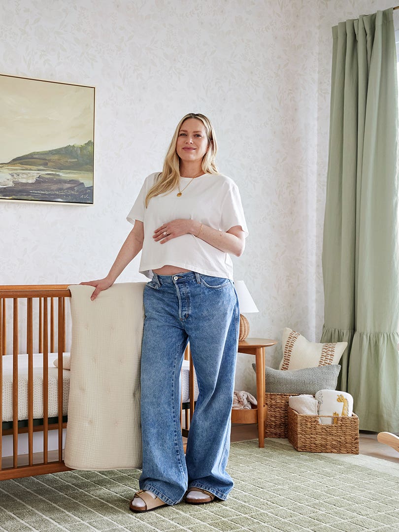 Pregnant woman posing in front of crib