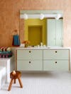 Bathroom with mint green cabinets and vivid striped towels
