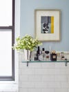 Blue bathroom wall with a floating shelf holding toiletries