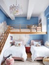Kids' bedroom with lofted bed and cloudy sky mural painted along back wall.