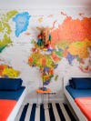 Kids' room with striped rug and big, colorful world map along back wall. 