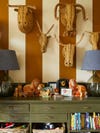 Green dresser with rattan animal heads hanging above
