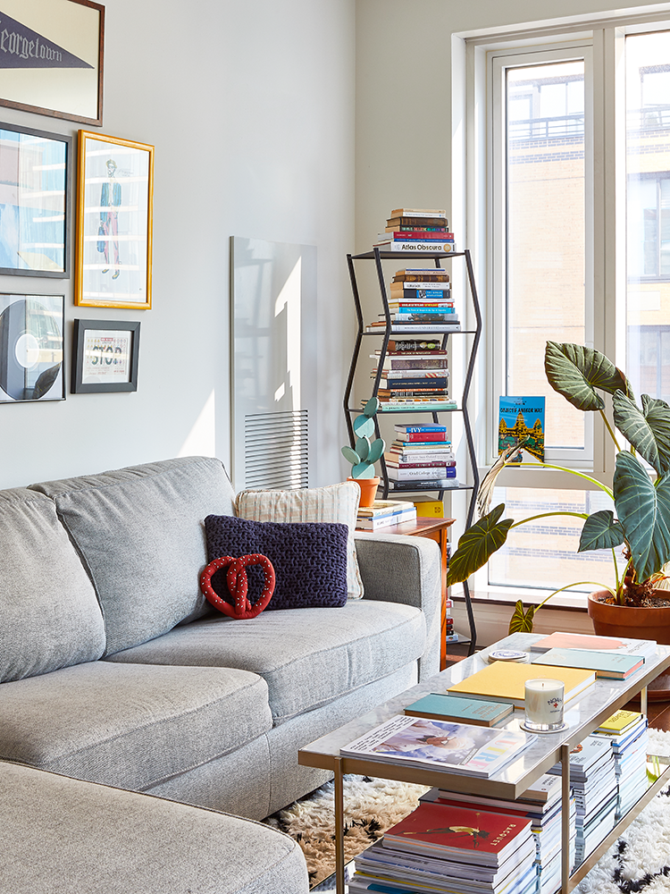 Living room with narrow storage coffee table covered in stacks of books.