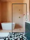 Bathroom with plaster pink walls and geometric tiled floor in pink, green, and black.