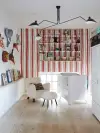 Nursery with red striped wallpaper and white crib.