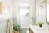 White and sage green bathroom with alcove shower. 