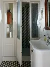 Small bathroom with black-and-white geometric tiled floor and shower.